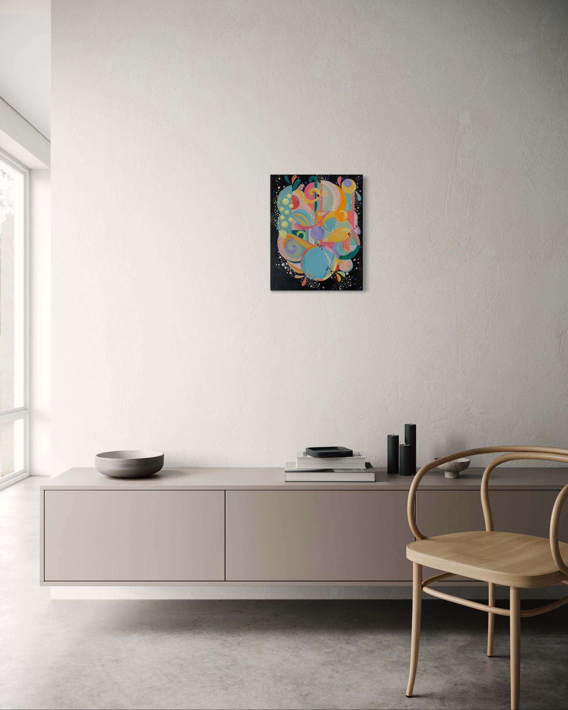 Modern interior with a colorful abstract painting on a white wall, a light-colored cabinet, and a wooden chair.